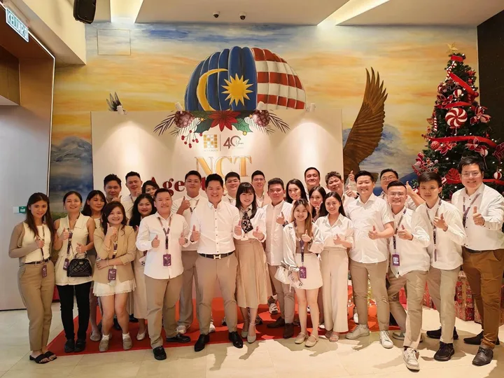A team posing together in front of a colourful indoor event display.