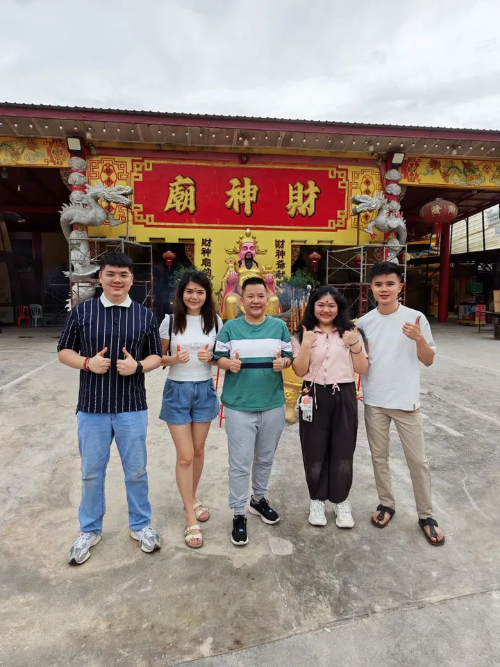 Five people posing outdoors in front of a traditional Chinese temple.