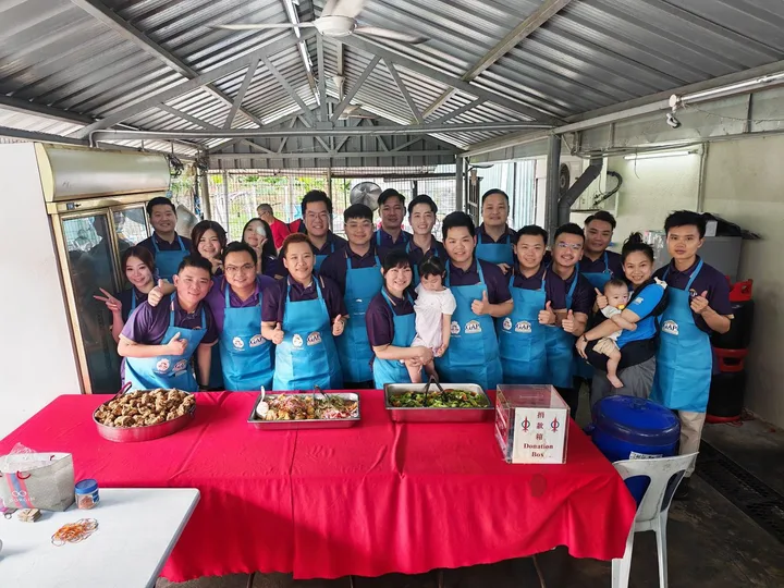 Team members in blue aprons posing behind trays of food and stacked boxes.