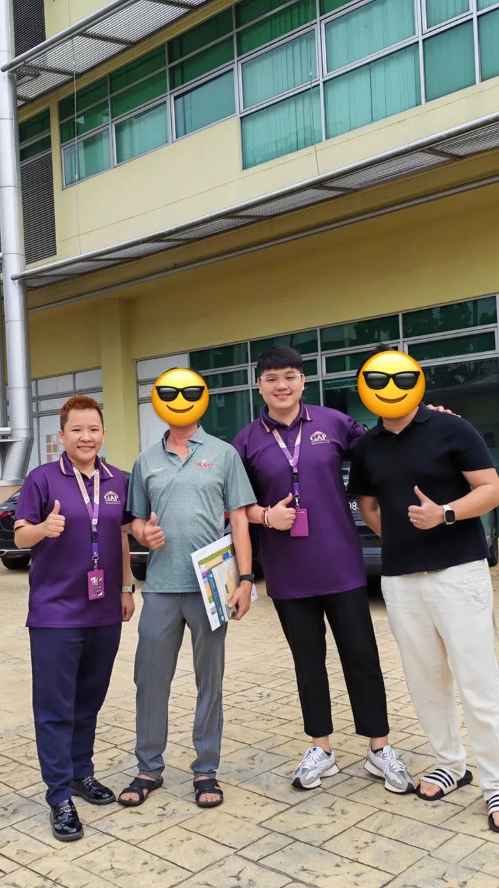 Four people posing outside a commercial building, with two faces covered by emoji.