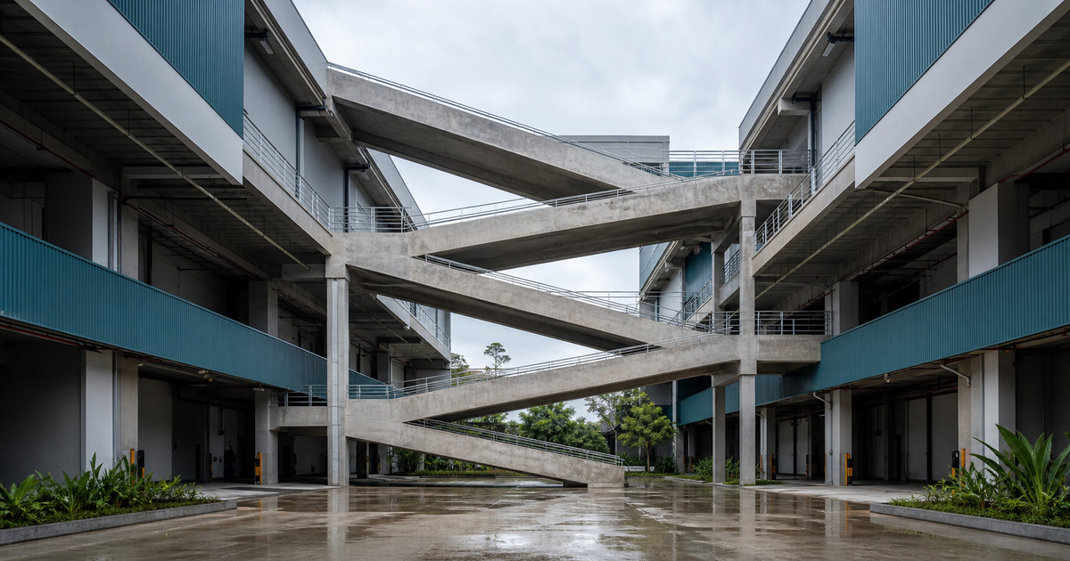 Low courtyard view of a multi-storey industrial ramp linking shared loading decks in Selangor